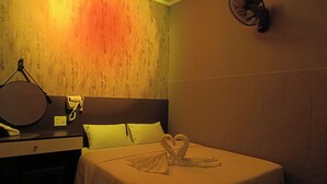A hotel room with a bed, a bedside table with a hairdryer, a mirror, and a towel art on the bed. - Japan Luna Hotel Binh Duong -BAYLUXURY (Ho Chi Minh City)