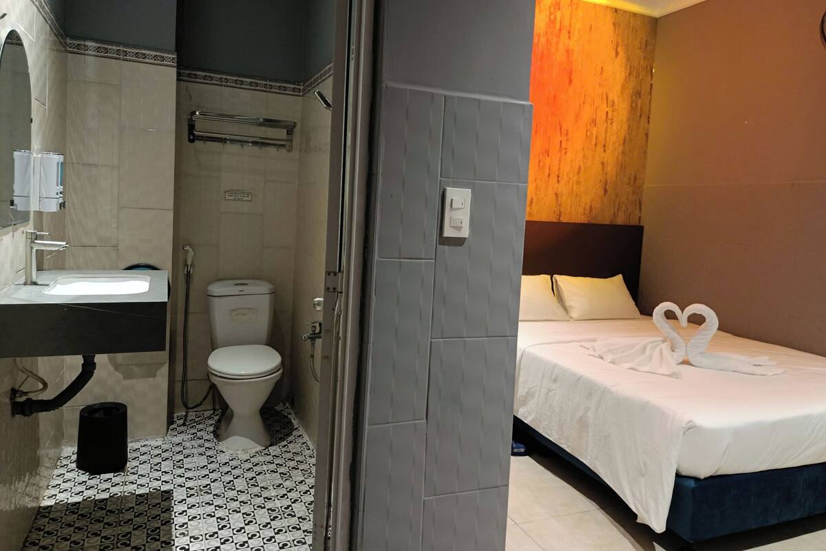 A hotel room with a bathroom, a bed with towels, and a shower.