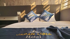 A hotel bed with pillows labeled "Japan Luna Hotel" and a blanket with the same branding. - Japan Luna Hotel Binh Duong -BAYLUXURY (Ho Chi Minh City)