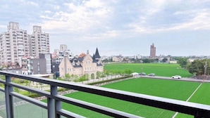 A view from a balcony overlooking a green field, a historic building, and modern high-rise buildings. - Aqua rooftop (Wujie)