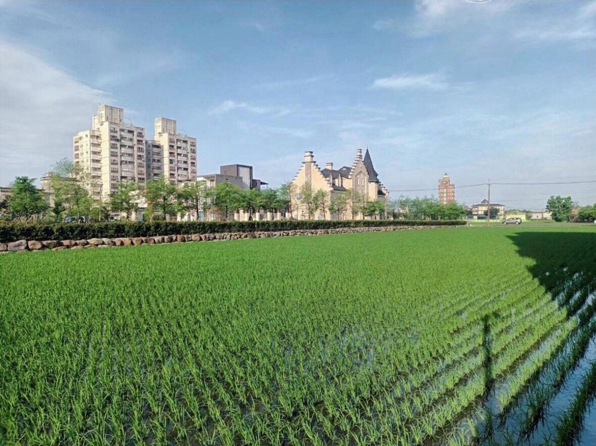A large green field with a historic building in the background.