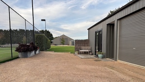 A gravel driveway leading to a building with a closed roller door, a bench, and potted plants.