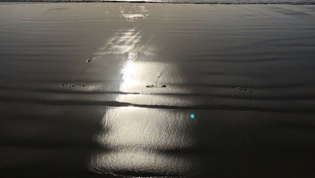 A beach with a calm sea and a clear sky.