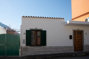 A building with a green gate, a wooden door, and a window with shutters.