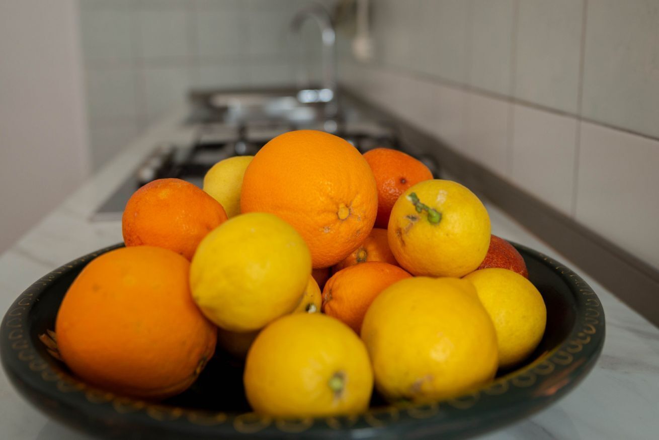 A kitchen with a sink and a bowl of oranges and lemons.