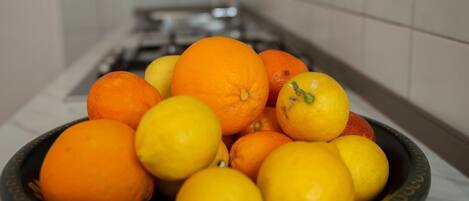 A kitchen with a sink and a bowl of oranges and lemons.
