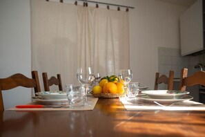 A dining table with chairs, a fruit bowl, and empty plates and glasses.
