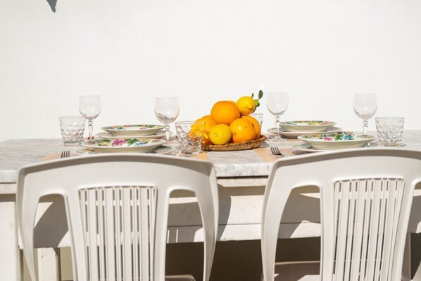 A dining table with a fruit bowl, plates, and glasses.