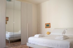 A hotel room with a bed, a wardrobe, a nightstand, and a framed picture on the wall.