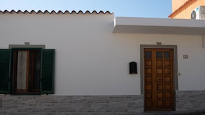 Un bâtiment à la façade blanche, avec une porte en bois et des volets verts.