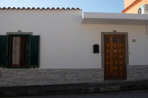 A building with a white facade, a wooden door, and green shutters.