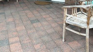 Une terrasse couverte avec un mur en briques, une porte blanche et deux chaises en bois.