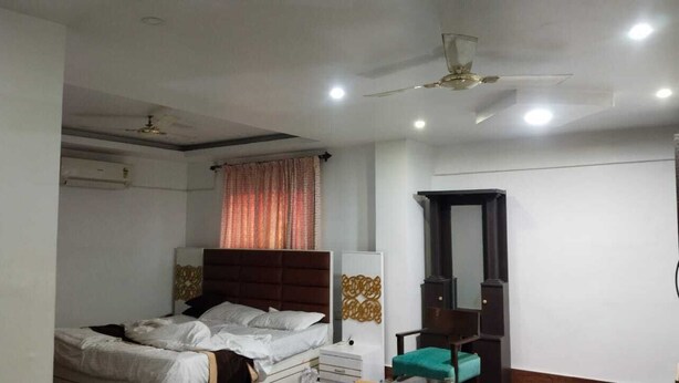 A bedroom with a bed, a wardrobe, a ceiling fan, and a window with curtains.