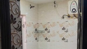 A small bathroom with a toilet, a shower, and a wall-mounted water heater.