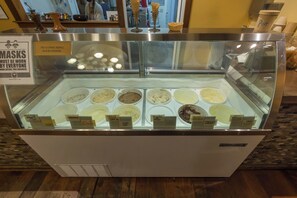 A food display case with various ice cream flavors labeled, and a sign indicating mask requirements. - The Abode at 124°West -Ultra Comfortable and Stylish Arcata Retreat (Arcata)