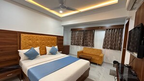 Ein modernes Hotelzimmer mit einem großen Bett, einer Couch, einem Fernseher und einem Deckenventilator.