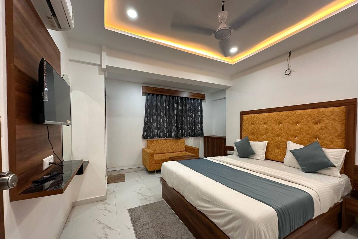 A modern bedroom with a large bed, a TV mounted on the wall, and a ceiling fan.