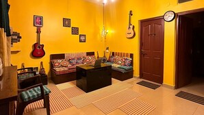 Un saló amb parets grogues, un sofà negre, una guitarra vermella i una taula de centre de fusta.