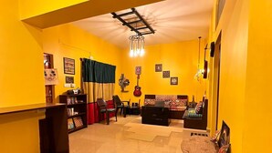 Un saló ben il·luminat amb parets grogues, un moqueta amb disseny de pedra, una guitarra i una taula de cafè.