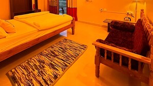 Una habitació amb un llit, un sofà, una televisió i una finestra amb cortines.