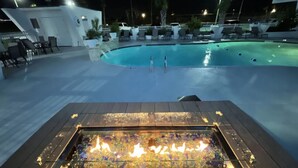 Un espace piscine doté de chaises longues et d’un foyer.