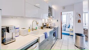 Une cuisine moderne avec des meubles blancs, un four encastré, un évier et une machine à café.
