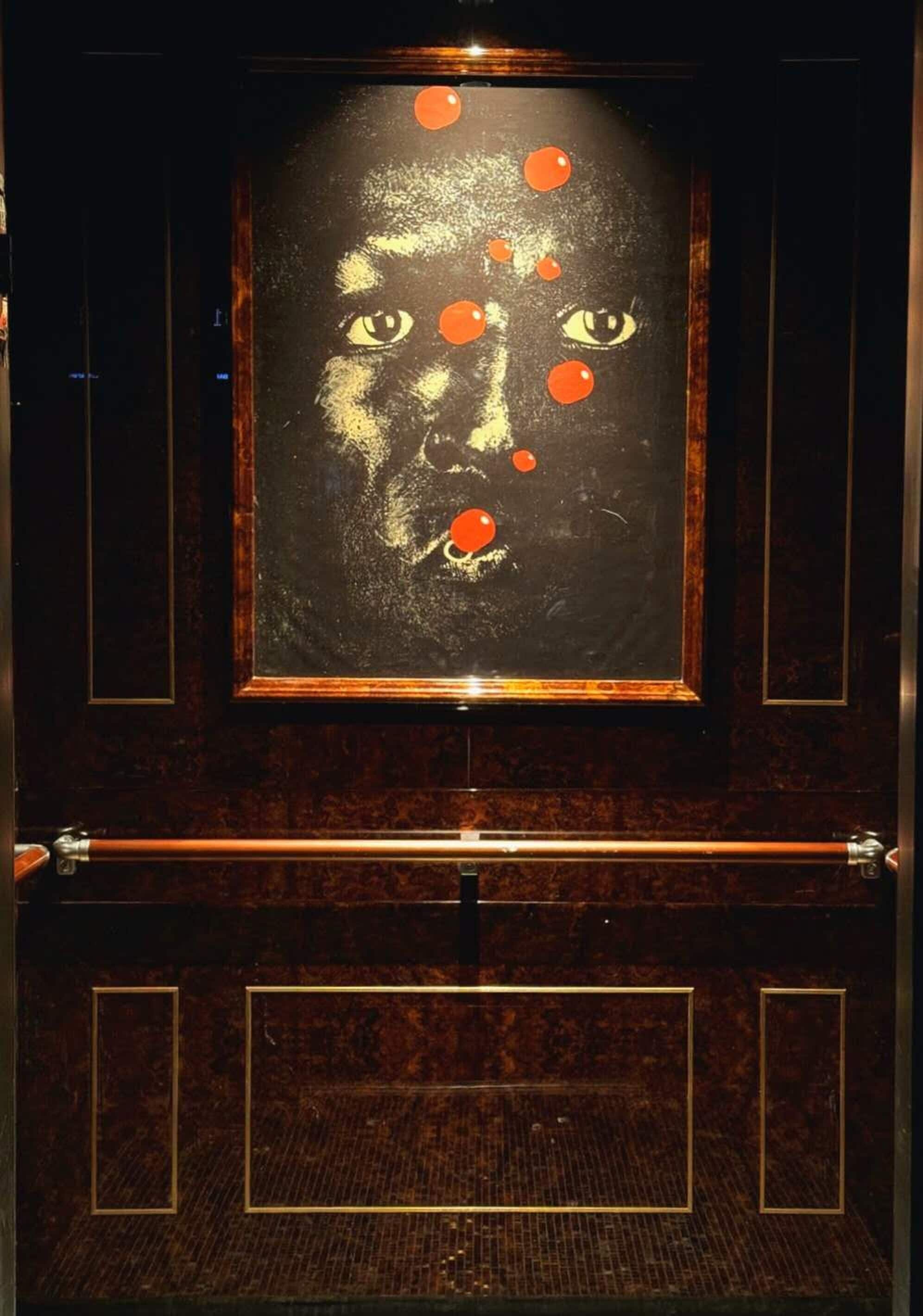 A door with a framed artwork featuring a face and orange dots.