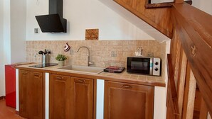 A kitchen with wooden cabinets, a sink, a microwave, and a black range hood.