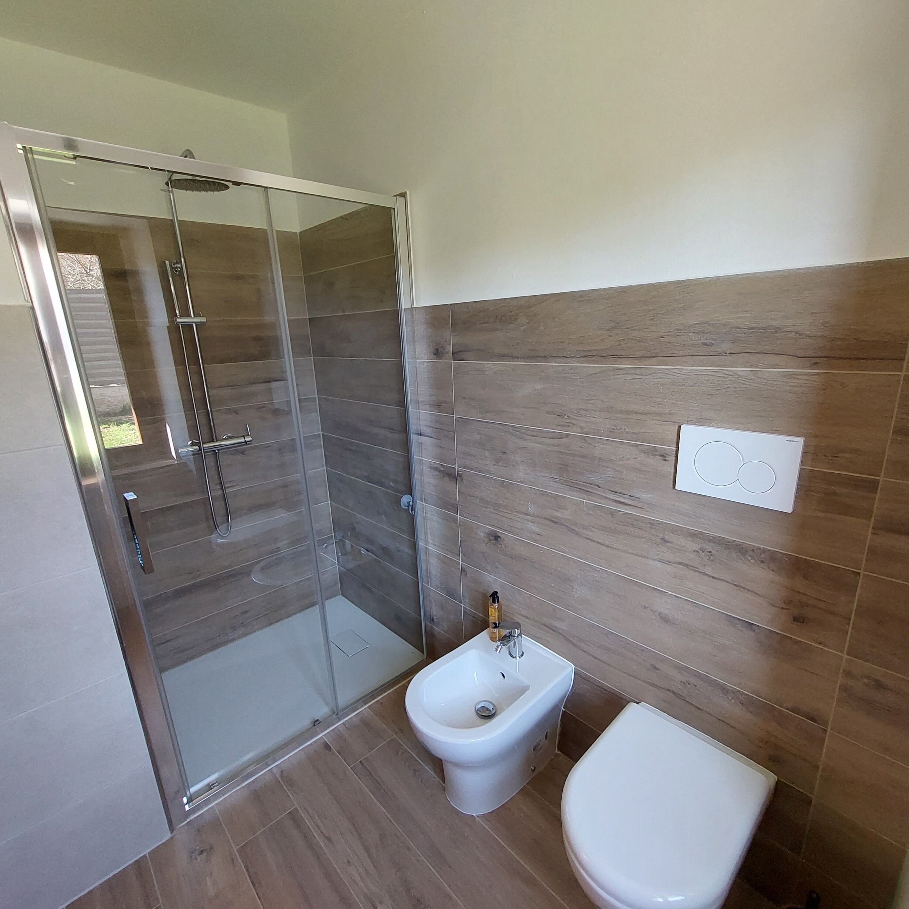 Une salle de bain moderne avec une douche à parois de verre, un bidet et des toilettes.
