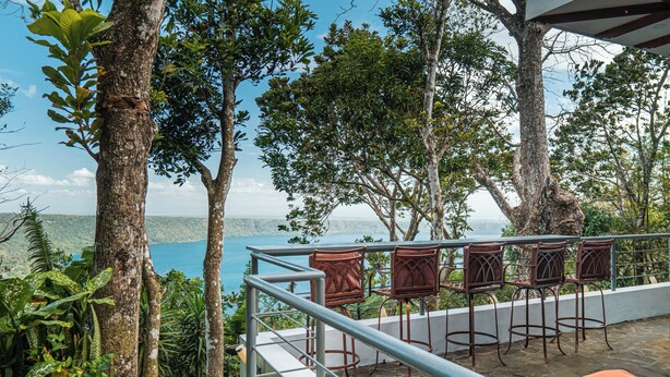Une terrasse avec vue sur la mer, entourée d’arbres et dotée de sièges extérieurs.