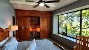 Une chambre avec un grand lit, une armoire en bois et une fenêtre donnant sur des arbres.