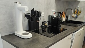 A modern kitchen with a black countertop, white cabinets, and a built-in sink. - Vacation apartment Olymp II, luxurious apartment in the heart of Bamberg (Bamberg)