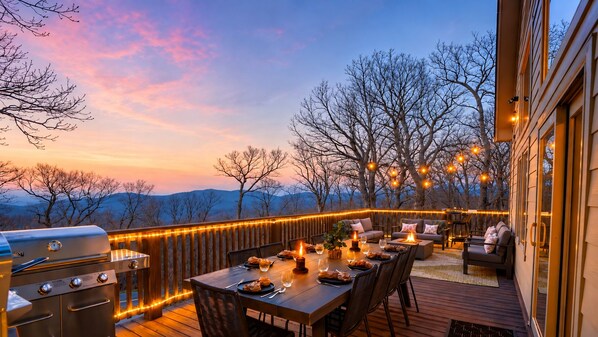 An outdoor deck with a dining table set for a meal, surrounded by chairs and a barbecue grill.