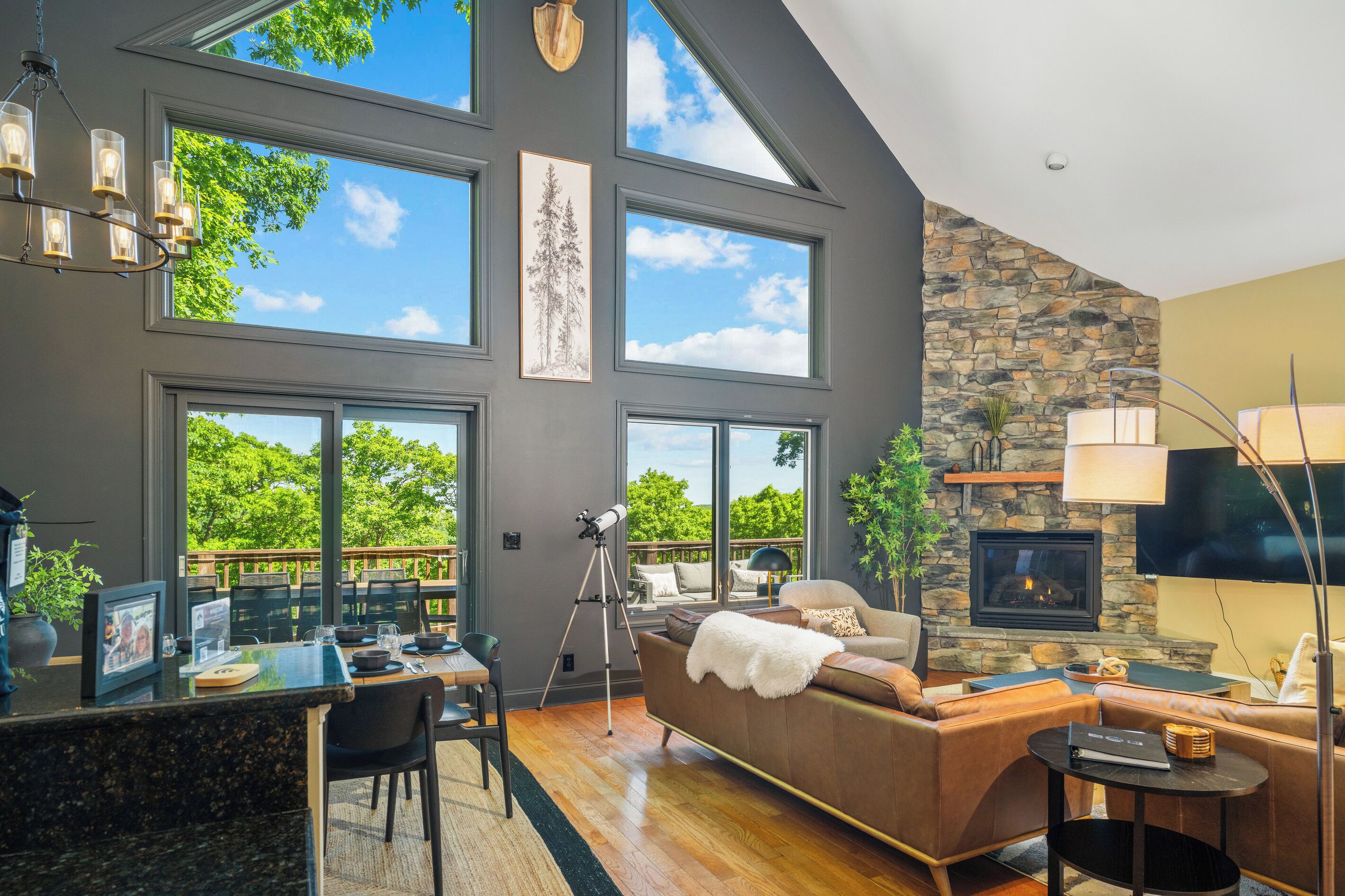 A modern living room with a fireplace, large windows, and a dining area with a view.