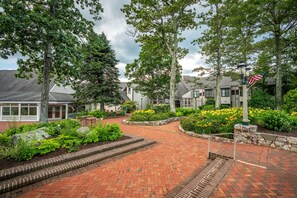 A brick pathway leading to a building with a flagpole and American flag.