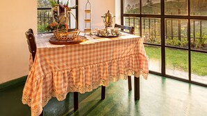 A dining area with a table set for four, a large window with a view of the countryside, and a framed picture on the wall. - Dover Cottage (Nuwara Eliya)