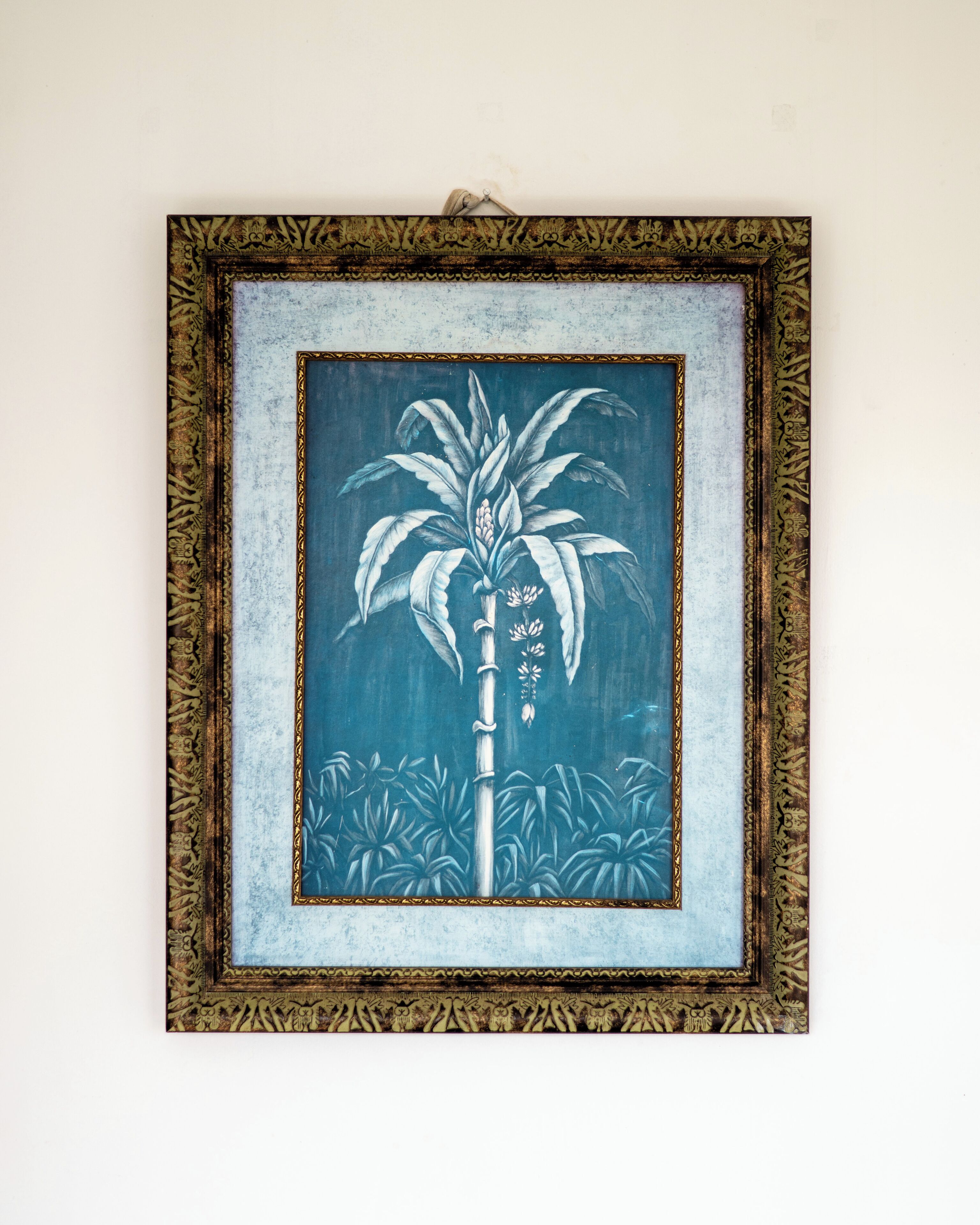 A framed artwork of a palm tree on a textured wall.