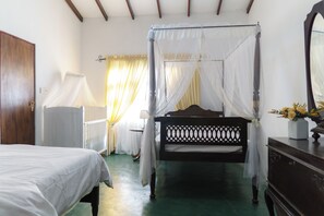 A bedroom with a four-poster bed, a wooden dresser, and a nightstand. - Dover Cottage (Nuwara Eliya)