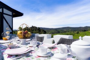 A table set for breakfast with a view of rolling hills. - Dover Cottage (Nuwara Eliya)