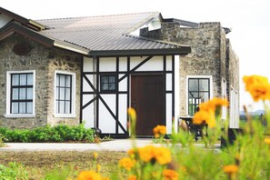 A stone building with a black and white exterior, a large wooden door, and a small porch. - Dover Cottage (Nuwara Eliya)