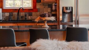 A modern kitchen with wooden cabinets, a stainless steel refrigerator, and a coffee machine. - COZY Cabin with Hot Tub - Near all in Hocking Hills (Logan)