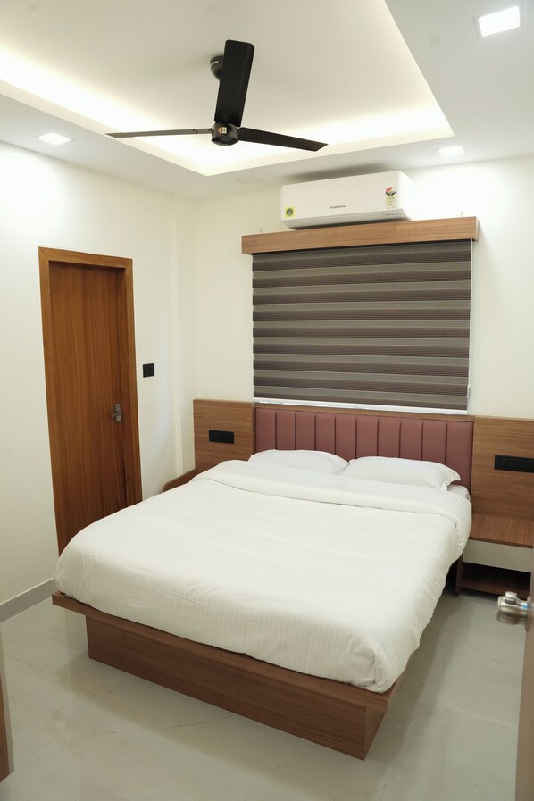 A modern bedroom with a wooden bed frame, a ceiling fan, an air conditioning unit, and a window with blinds. - Theeram Residency (Koyilandy)