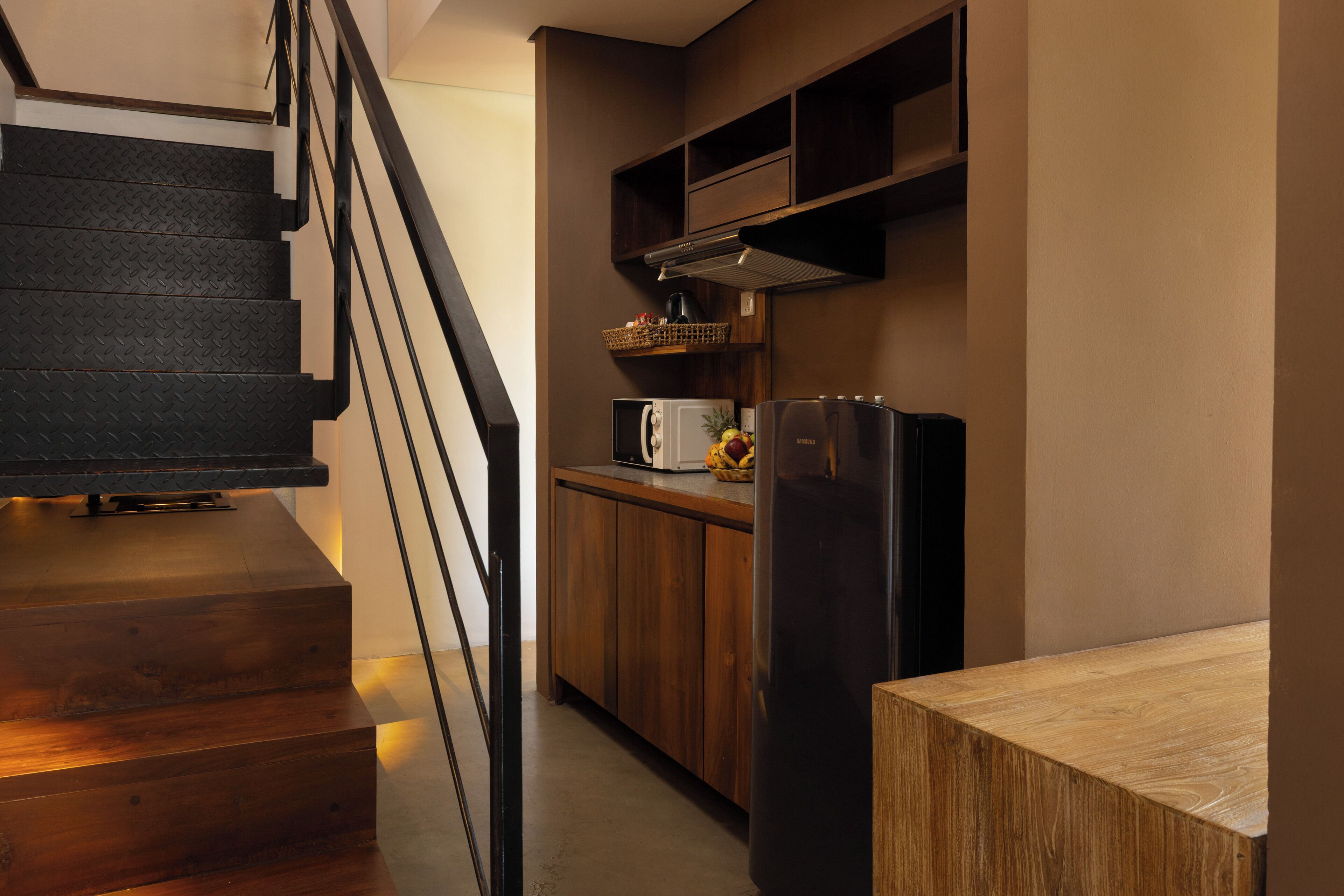 A modern kitchen with wooden cabinets, a stainless steel refrigerator, and a microwave.