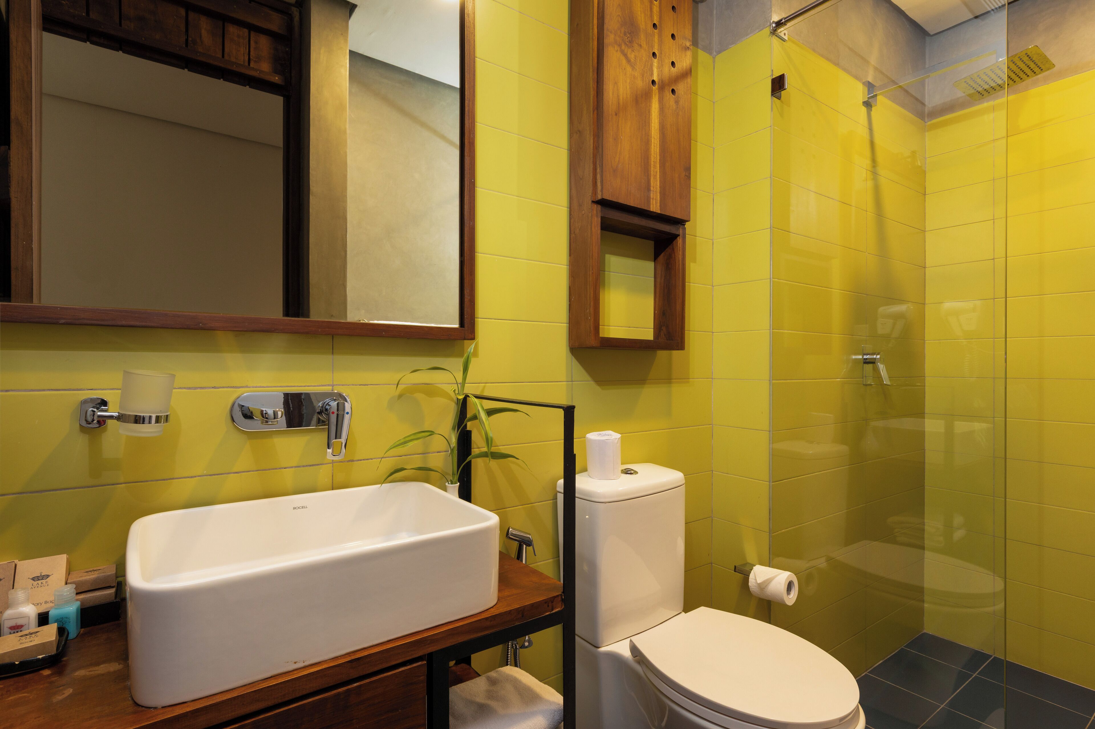 Un baño con lavamanos blanco, inodoro y cabina de ducha con mampara de vidrio.