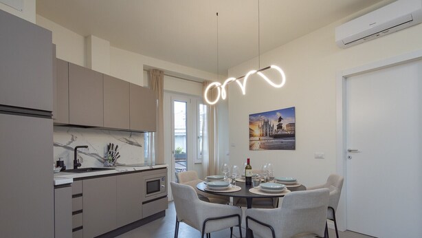 A modern kitchen with a dining area, a pendant light, and a painting on the wall. - Prina  - Spacious 2BDR, Arco - Sempione Area (Milano)