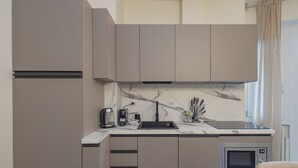 A modern kitchen with a marble backsplash, a built-in microwave, and a coffee maker. - Prina  - Spacious 2BDR, Arco - Sempione Area (Milano)