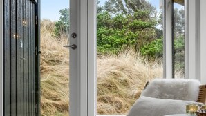 A room with a wooden door, a white chair with a fluffy white cushion, and a small round table with a candle. - "Gundborg" - 200m from the sea by Interhome (Saltum)
