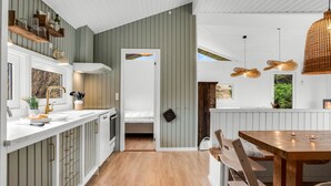 A modern kitchen with white cabinetry, wooden countertops, and a dining area with a wooden table and chairs. - "Gundborg" - 200m from the sea by Interhome (Saltum)