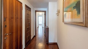 A hallway with wooden doors, a framed painting, and a light fixture on the ceiling. - Beautiful House In Porta Soprana Genova (Genoa)