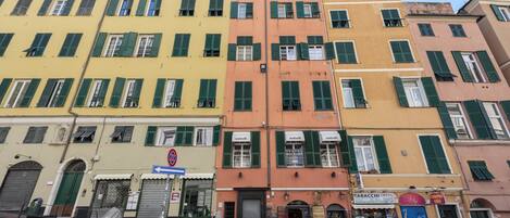 A row of colorful buildings with green shutters, a visible storefront, and parked motorcycles.